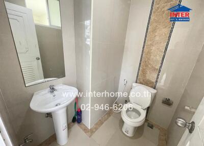 Modern bathroom with sink, toilet, and tiled wall