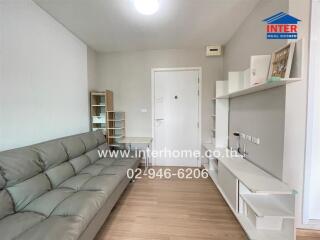 Modern living room with gray couch, shelves, and door