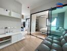 Modern living space featuring a small sitting area, a sliding glass door separating the bedroom, and a compact kitchen area.