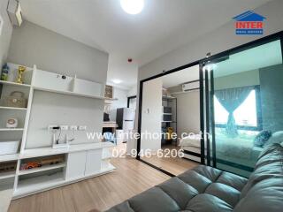 Living area with shelving and sliding glass door leading to a bedroom