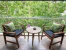 Cozy balcony with chairs, table, and greenery view