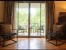 Living room with two chairs, a wooden floor, and a view to a balcony.