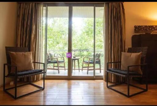 Living room with two chairs, a wooden floor, and a view to a balcony.