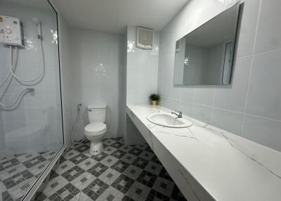 Modern bathroom with large mirror, sink, shower, and toilet