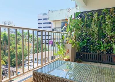 A sunny and spacious balcony featuring plants and a glass-top table