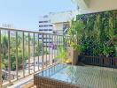 A sunny and spacious balcony featuring plants and a glass-top table