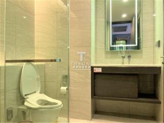 Modern bathroom with toilet, shower, and a lighted mirror