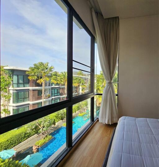 Bedroom with a view of the pool and garden area outside large windows.