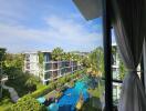 View of residential buildings with a swimming pool and greenery from a window