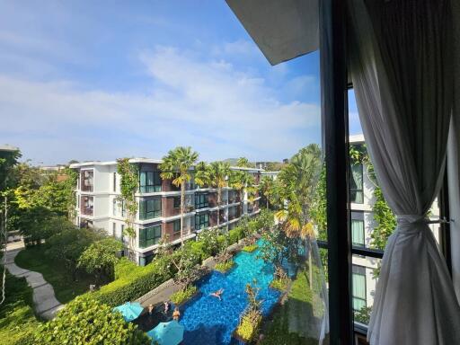 View of residential buildings with a swimming pool and greenery from a window