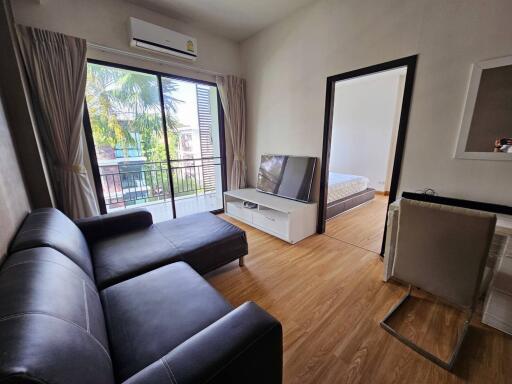 Living room with sofa, TV, and access to balcony