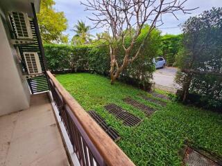 View of a lush green garden with trees and plants from a balcony.