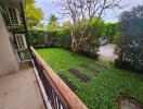 View of a lush green garden with trees and plants from a balcony.