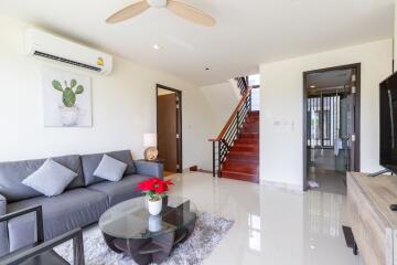 Modern living room with grey sofa, glass coffee table, and staircase