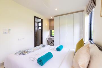 Bright and modern bedroom with large window, neatly made bed, and ample storage space.