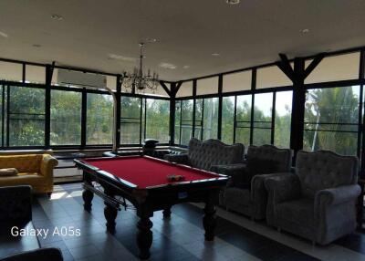 Spacious living area with a pool table, large windows, and multiple seating options