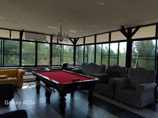 Spacious living area with a pool table, large windows, and multiple seating options