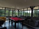 Spacious living area with a pool table, large windows, and multiple seating options