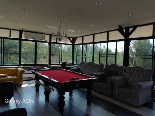 Spacious living area with a pool table, large windows, and multiple seating options