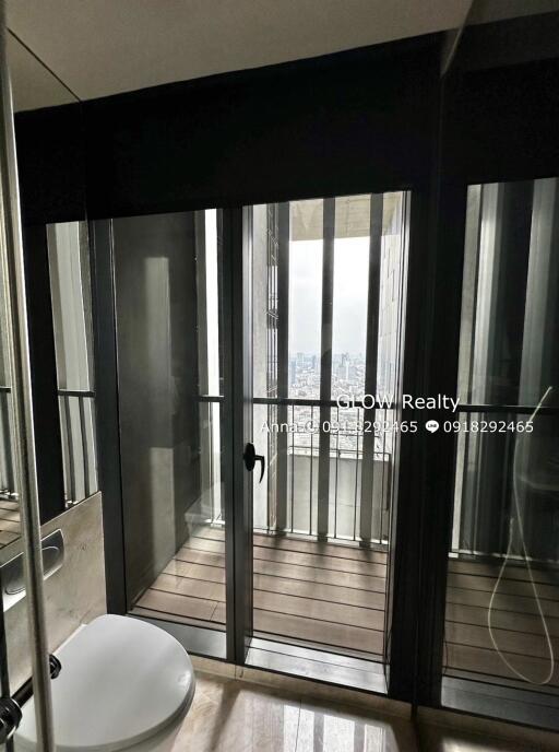 Modern bathroom with a glass door leading to a balcony and a view of a city