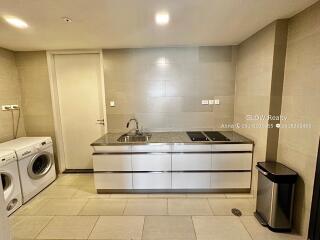 Modern laundry room with washing machine and dryer, large countertop and storage cabinets.