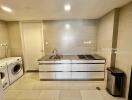 Modern laundry room with washing machine and dryer, large countertop and storage cabinets.