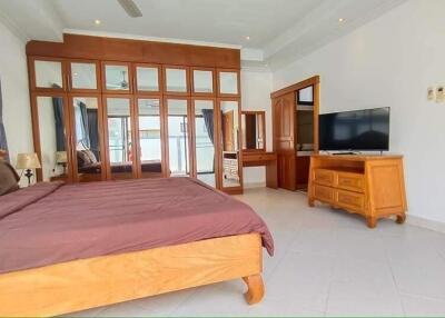 Spacious bedroom with wooden furniture and large mirror wardrobe