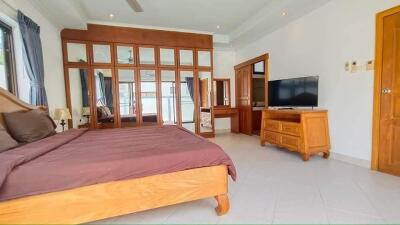 Spacious bedroom with wooden furniture and large mirror wardrobe
