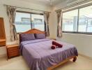 Comfortable bedroom with a double bed, large windows, and a vanity desk