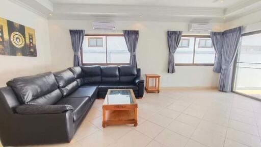 Spacious living room with black leather sectional sofa and coffee table