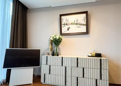 Living room with a wall-mounted painting, a modern cabinet, TV stand, and decor