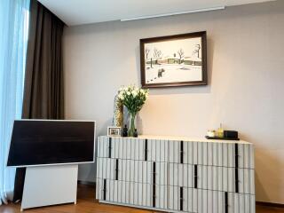Living room with a wall-mounted painting, a modern cabinet, TV stand, and decor