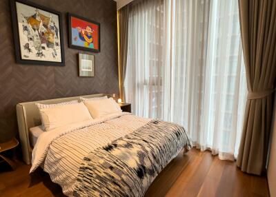 Cozy bedroom with modern decor, large window, and hardwood floors