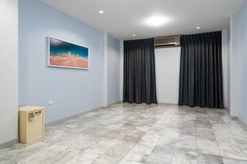 Spacious living room with tiled floor, wall-mounted painting, and full-length curtains.