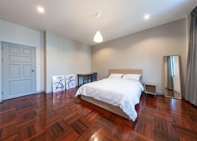 Spacious bedroom with wooden flooring, modern decor, and natural light