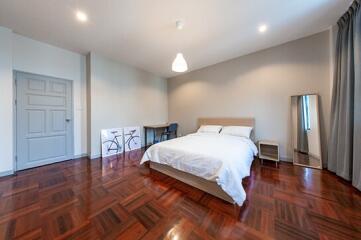 Spacious bedroom with wooden flooring, modern decor, and natural light