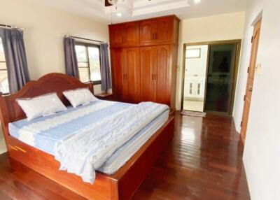 Spacious bedroom with wooden floors, large bed, ceiling fan, and ample closet space