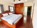 Spacious bedroom with wooden floors, large bed, ceiling fan, and ample closet space