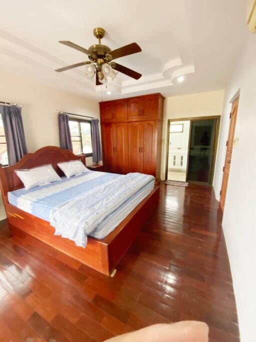 Spacious bedroom with wooden floors, large bed, ceiling fan, and ample closet space