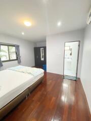 Spacious bedroom with wooden flooring and ample natural light