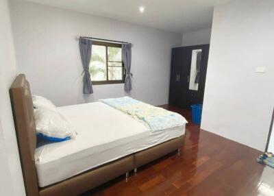 Spacious and well-lit bedroom with hardwood flooring and large window.