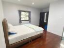 Spacious and well-lit bedroom with hardwood flooring and large window.