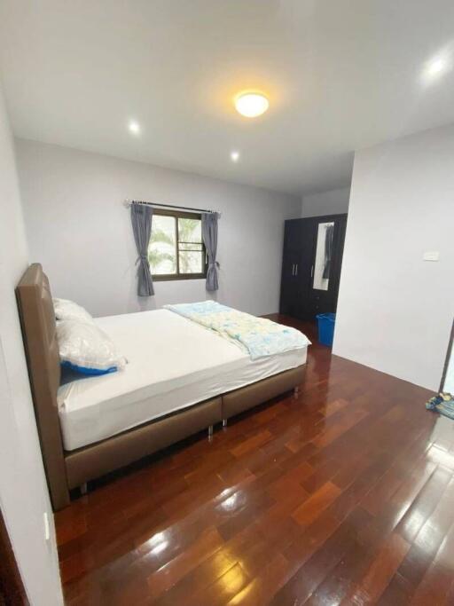 Spacious and well-lit bedroom with hardwood flooring and large window.