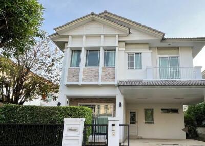 Two-story white house with a carport and garden