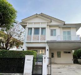 Two-story white house with a carport and garden