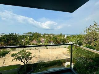 This is a view from the balcony overlooking lush greenery and distant structures