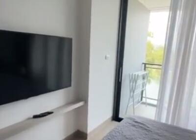 Bedroom with wall-mounted TV and balcony