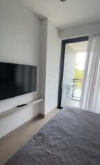 Bedroom with wall-mounted TV and balcony