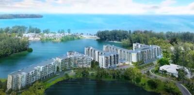 Aerial view of modern beachfront condominium buildings surrounded by greenery with a beautiful coastal backdrop