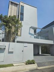 Modern three-story building with driveway and greenery